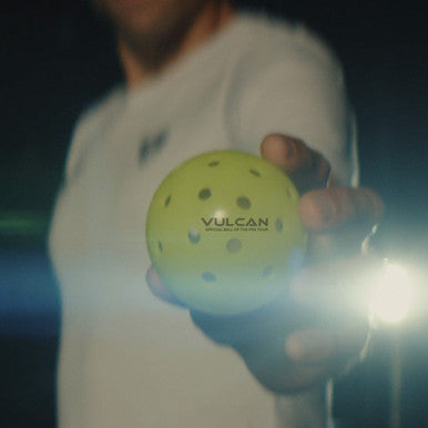 Vulcan VPRO Flight Outdoor Pickleball in the hand of a Vulcan pro pickleball player.